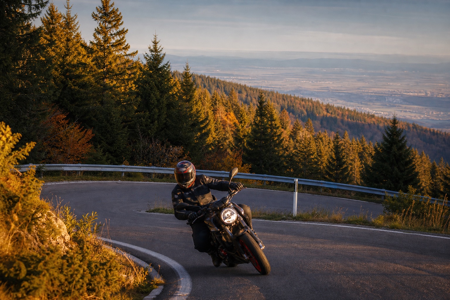 Schmale Kammstraße im Schwarzwald mit Fichten und Fernblick über die Rheinebene, ein Motorrad in Schräglage in der Kurve